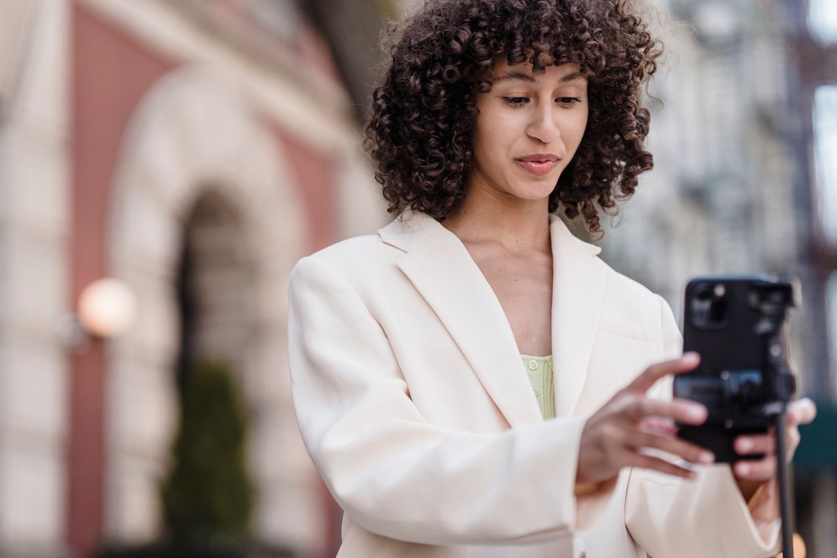A creator filming herself with her phone on a city street